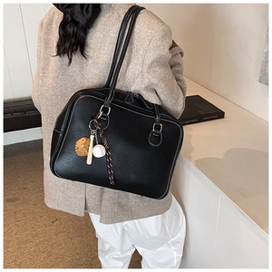 Detail of black faux leather tote bag featuring a creative baseball-themed charm set