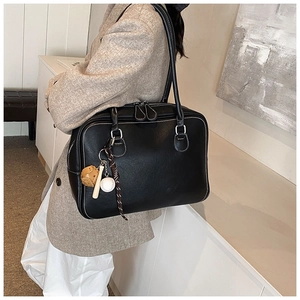 Detail of black faux leather tote with white contrast stitching and cute decorative charms