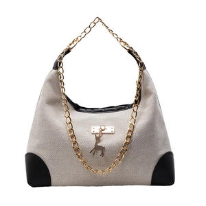 Women's woven tote bag with gold chain strap and deer pendant on white background