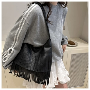 Detail shot of black crossbody bag featuring dual-layered long fringe and soft leather texture