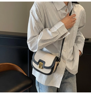 Detail of vintage saddle bag with cream canvas, black leather trim and gold buckle