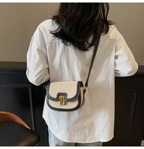 Detail of retro canvas saddle bag with black leather trim and matte gold metal clasp buckle