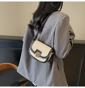 Detailed view of vintage canvas saddle bag with black leather trim and gold metal lock