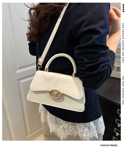 Detail of minimalist cream beige crossbody bag featuring golden oval twist lock closure