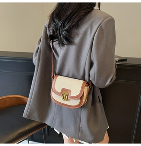 Chic saddle bag shown on model with beige canvas and brown leather trim details