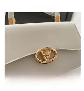 Close-up of elegant white leather handbag with golden V-shape metal buckle detail