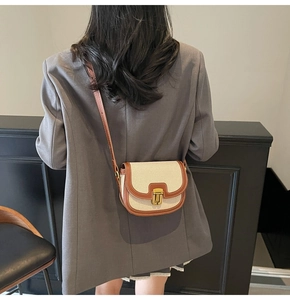 Close-up of retro canvas and brown leather crossbody bag with golden metal buckle clasp