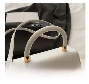 Detail of white leather handbag with textured lychee grain and golden metal handle hardware