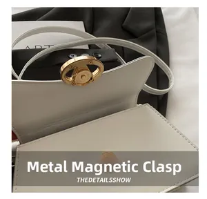 Close-up of premium magnetic hardware clasp on a minimalist cream faux leather handbag