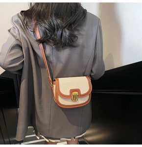 Detail view of contrast color saddle bag with gold metal clasp on a grey blazer suit