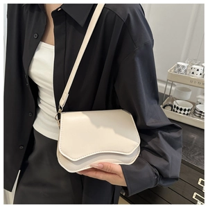 Detail of off-white crossbody bag with wavy flap design and gold metal hardware