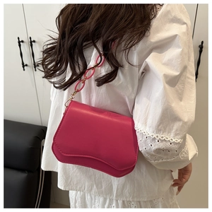 Detail view of pink shoulder bag with wavy edge design and thick chain strap