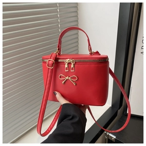 Detail of red leather box bag with gold bow clasp and metal zipper closure