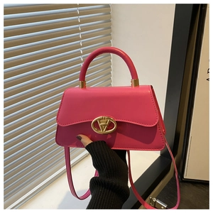Detail view of pink trapezoid handbag with gold rotating lock and long shoulder strap