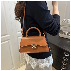 Brown leather crossbody bag shown on person for size perspective in interior setting