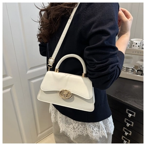 Minimalist beige leather shoulder bag with gold metal buckle shown on a model