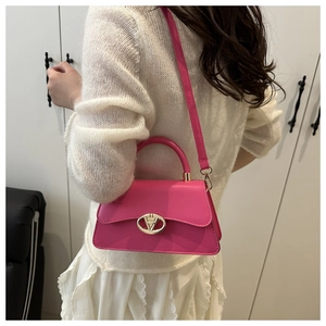 Gros plan d'un sac bandoulière rose avec boucle dorée porté par un mannequin en salle