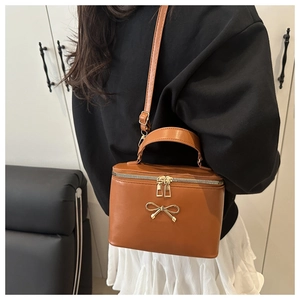 Rear view of model wearing the brown vanity bag with gold bow and adjustable strap