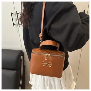 Detail of caramel PU leather box bag with gold metal bow clasp and adjustable strap