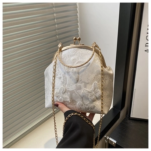 Detailed close-up of white lace handbag with butterfly embroidery and golden clasp