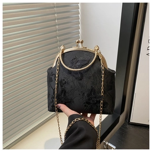 Detail of vintage black bag with butterfly embroidery and golden metal hardware