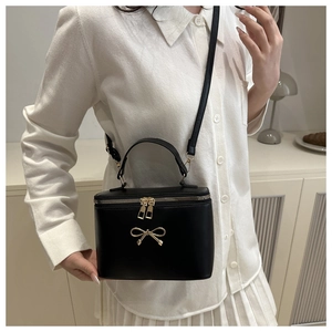Detail of vintage black box bag with golden bow hardware and dual zipper closure