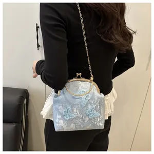 Detail view of a vintage blue hand-held bag with 3D butterflies and embroidery