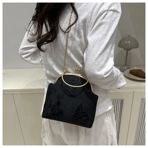Close-up of black lace handbag featuring 3D butterfly embroidery and gold metal clasp