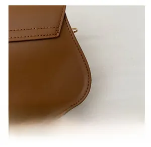 Detail view of precise stitching on brown faux leather crossbody bag with metal accents