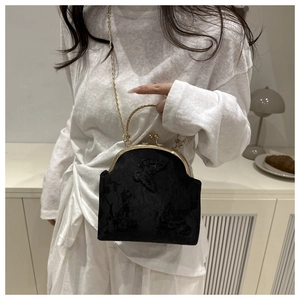 Detailed view of black butterfly embroidery and gold metal chain on a retro handbag