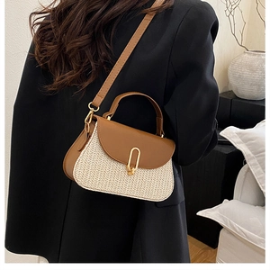 Détail d'un sac bandoulière en paille avec garniture en similicuir brun et boucle dorée