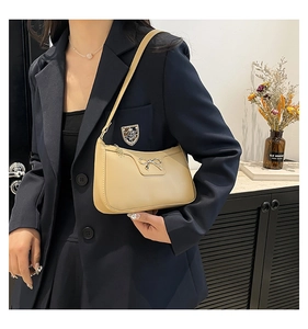 Détail d'un sac à épaule en cuir beige avec fermoir nœud métallique et bandoulière
