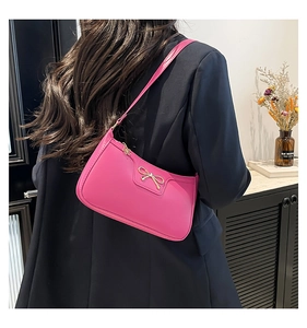 Close-up of bright pink shoulder bag with elegant gold bow detail and metallic zipper