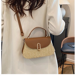 Detail of a two-tone woven crossbody bag with brown leather trim and gold hardware