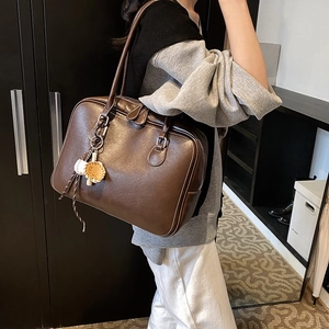 Retro dark brown large tote bag with baseball charm pendant shown in a side-view lifestyle shot