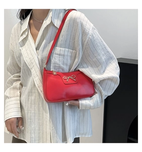 Détail du sac en cuir PU rouge avec nœud doré et charme de fermeture fleurie