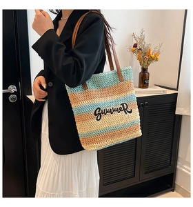 Detail of striped woven bucket bag with Summer embroidery and leather handles