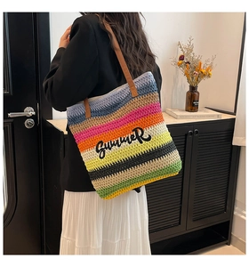 Detail of colorful striped woven tote bag featuring embroidered SUMMER text and leather strap