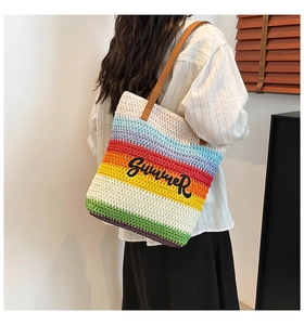 Detail of rainbow striped straw tote bag with black Summer embroidery and leather handles
