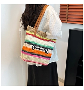 Detail of colorful striped straw tote bag with Summer embroidery and leather handles