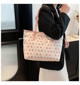 Detail of white bear print tote bag with pink straps worn by a model in interior setting