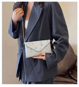 Detail of white envelope crossbody bag with blue cloud pattern and golden chain strap