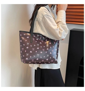 Detail of large brown shoulder bag with floral and bow patterns worn by a model