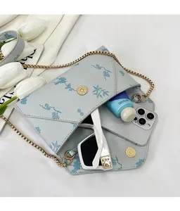 Detail of light blue floral envelope bag showing spacious interior with golden chain strap