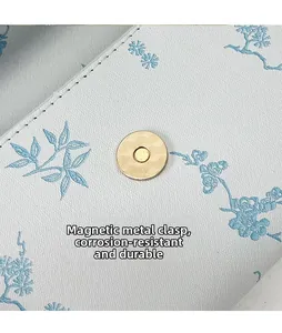 Macro shot of magnetic golden clasp on floral textured leather envelope bag