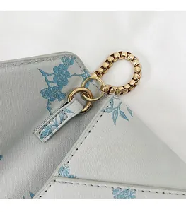 Detail of the golden metal strap connection ring on a blue floral texture leather bag