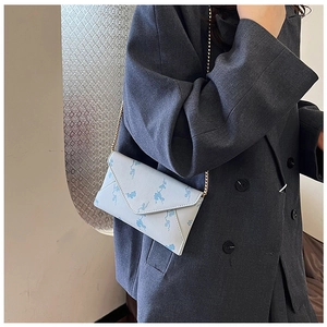 Close-up of light blue envelope bag with vintage patterns and gold chain strap