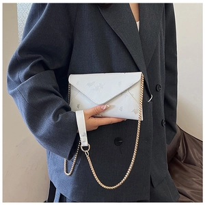 Close-up of a white envelope bag with floral patterns and a gold chain strap