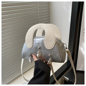 Detail view of silver barrel bag with white handles and hanging pearl charms