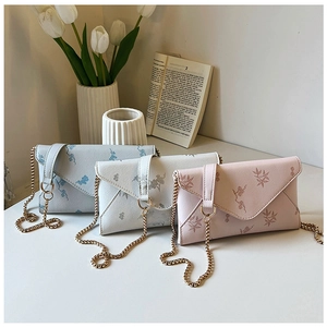 Three envelope crossbody bags with leaf textures and gold chains in soft pastel colors